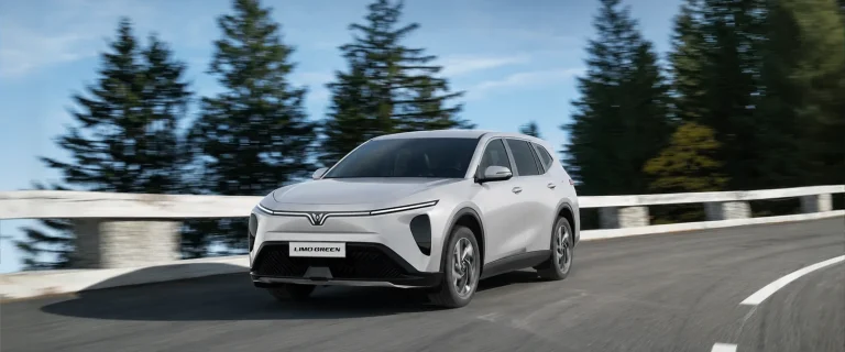 VinFast Limo Green màu trắng vào cua trên đường giữa rừng thông