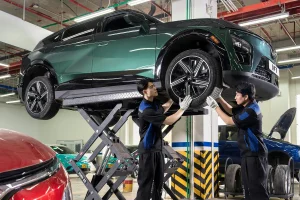 Kỹ thuật viên dịch vụ VinFast kiểm tra gầm và bánh xe ô tô điện trên cầu nâng